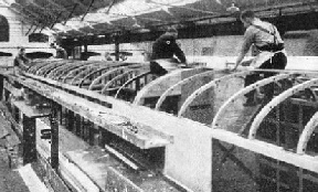 A VIEW of men in the process of fitting a carriage roof