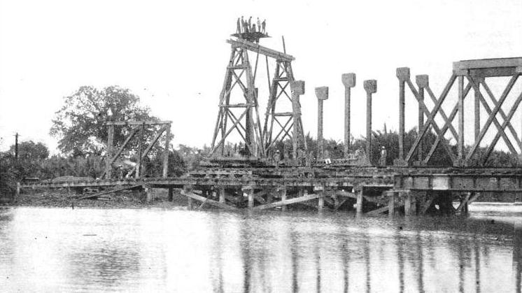 ERECTING THE GIRDERS of the large Langgar bridge in Kedah, Malaya