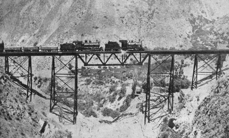 A DOUBLE-HEADED FREIGHT TRAIN crossing the slender Challape Bridge